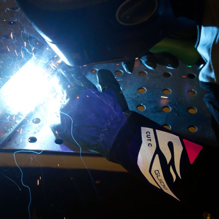 Person welding metal with protective gear and wearing Guide 3571 welding gloves