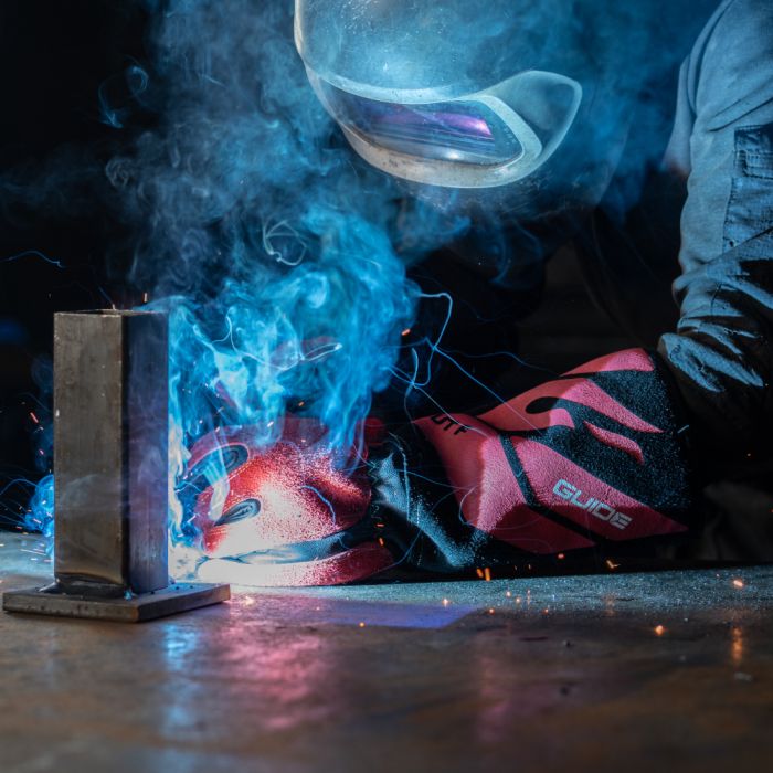 Person welding with protective gear welding gear showing the guide 3572 red back welding gloves  in a workshop setting