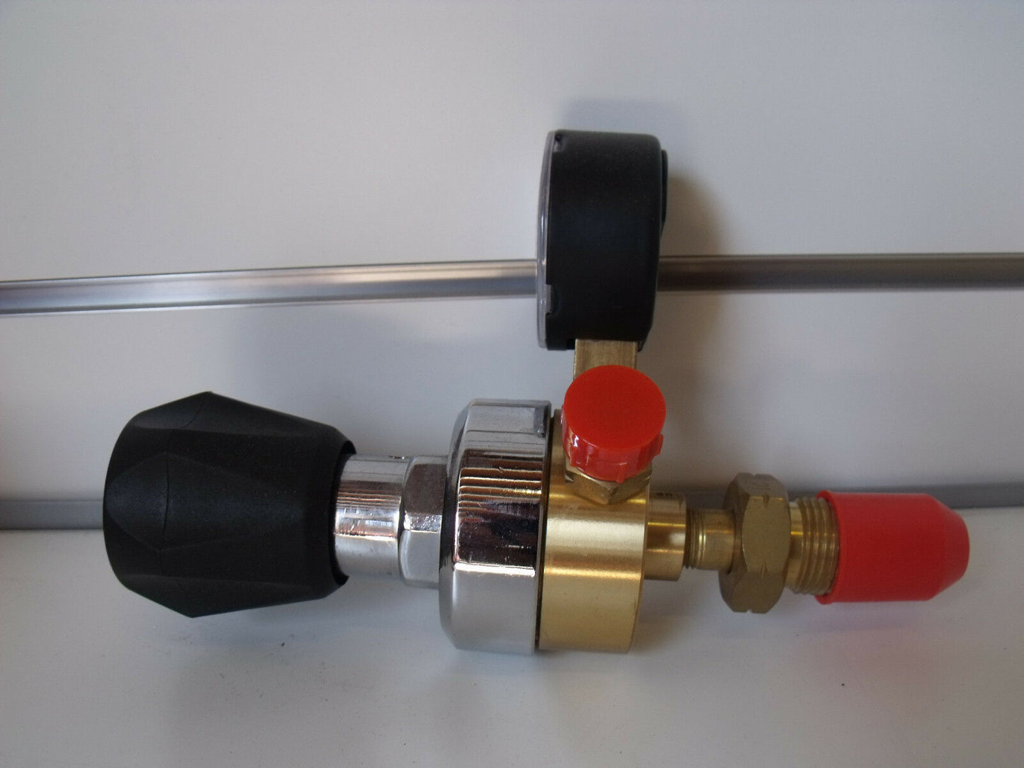 An LPG regulator with a rear-entry design, featuring a silver body, black knob, and red adjustment screw.