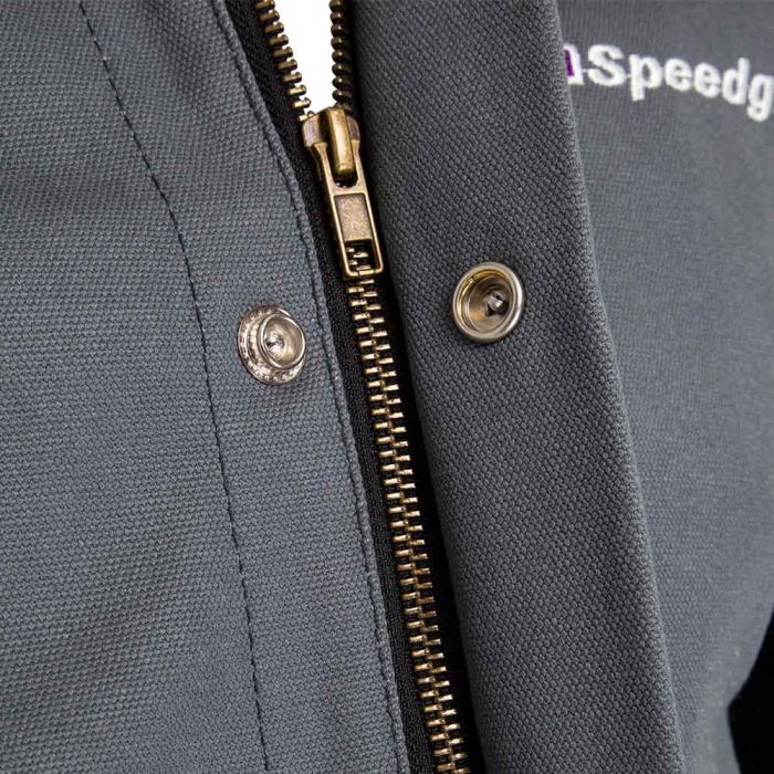 Close-up of a gray jacket with a zipper and Speedglas branding 